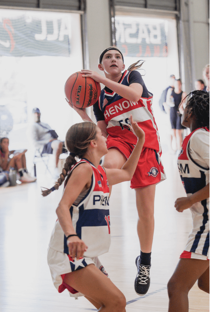 Some small girls playing basket ball in a court
