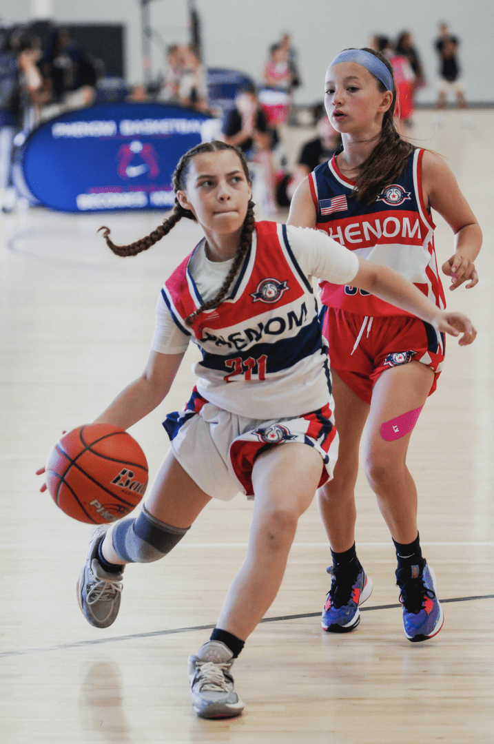 Two girls running with a basket ball in a court